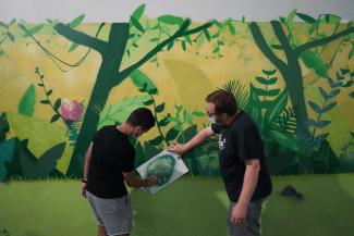 Photo de deux participants en train de graffer le mur à l'aide d'un pochoir